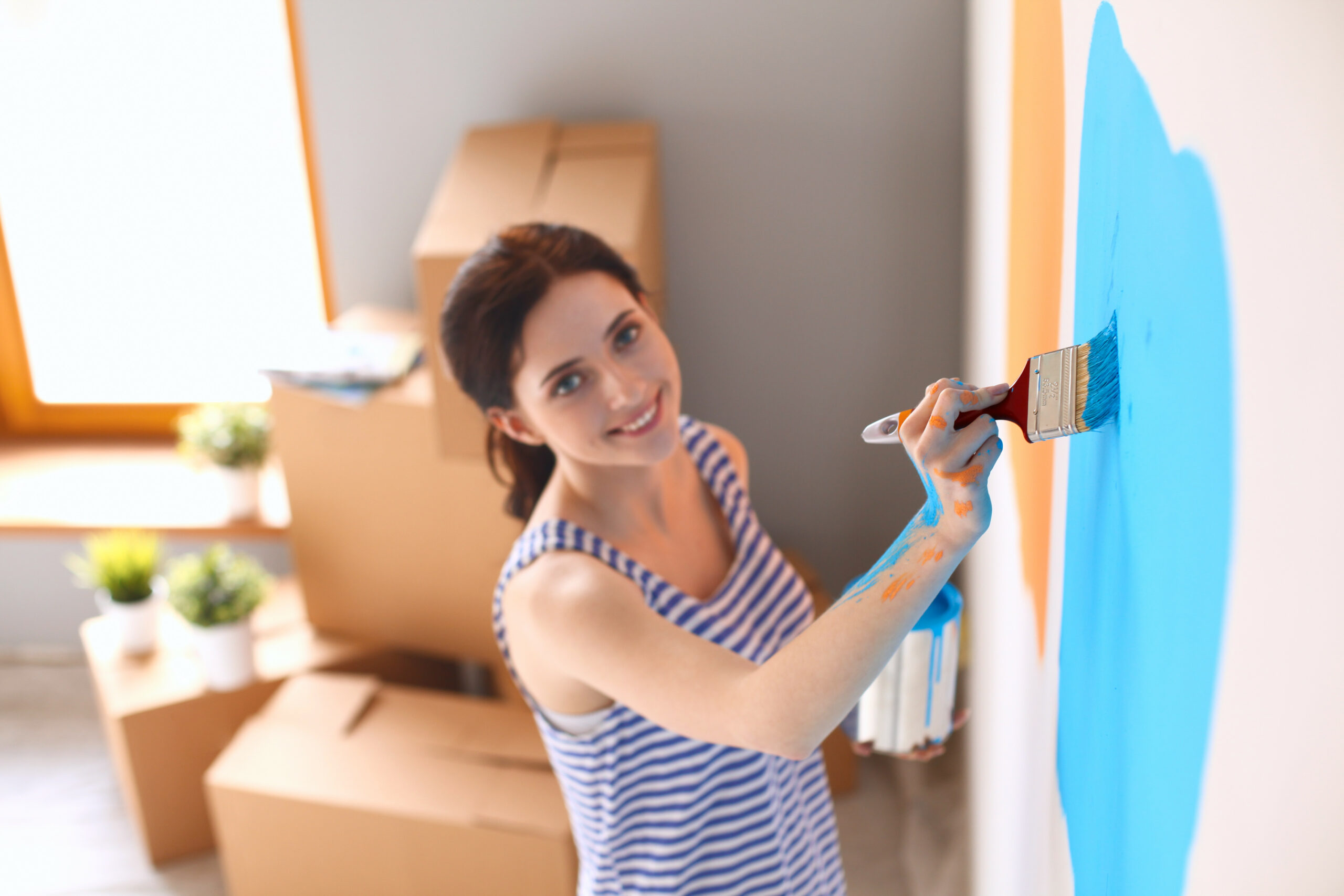 Happy smiling woman painting interior wall of new house